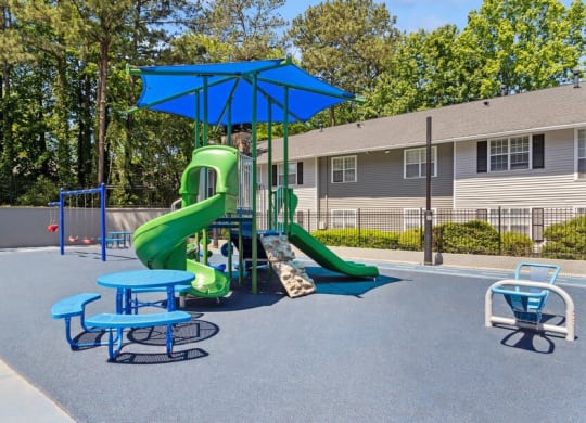 Community Playground with a Slide, Swing Set and Blue Canopy at Dunwoody Village Apartments in Atlanta, GA.
