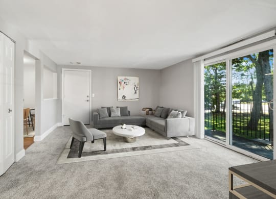 Model living room with a gray couch and a white coffee table in front of a sliding glass door