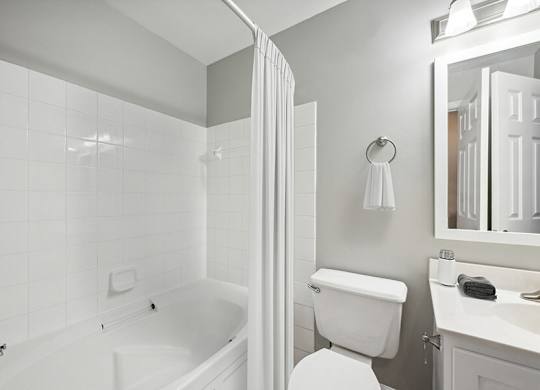 Model Bathroom with White Cabinets, Wood-Style Flooring and Shower/Tub at Dulles Green Apartments located in Herndon, VA.