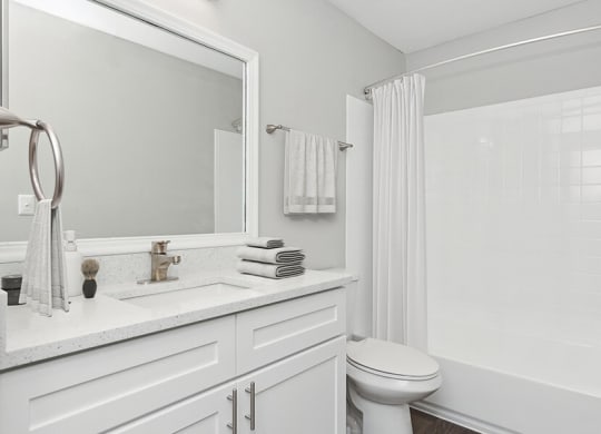 Model Bathroom with White Cabinets, Wood-Style Flooring and Shower/Tub at Grand Pavilion Apartments in Tampa, FL.