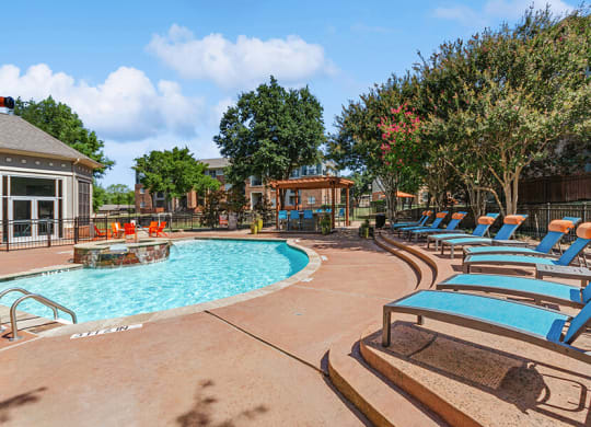 Community Swimming Pool with Pool Furniture at Belmont at Duck Creek Apartments in Garland, TX.