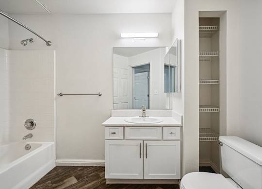 Model Bathroom with Wood-Style Flooring, White Cabinets, and Shower/Bathtub at Altitude on Fifth Apartments located in Salt Lake City, UT.