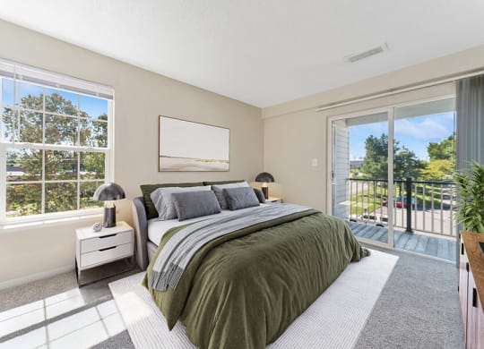 Model Bedroom with Carpet and Patio at The Commons at Haynes Farm Apartments in Boston, MA.