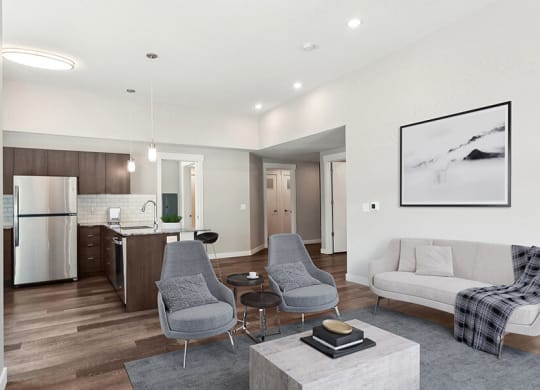 Model Living Room with Wood-Style Flooring and View of Kitchen at Seven Skies Apartments located in Sandy, UT.