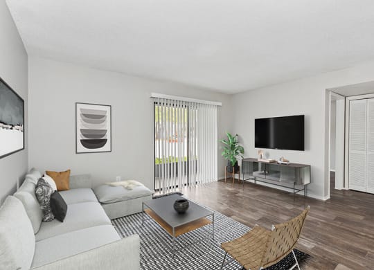 Model Living Room with Wood-Style Flooring and Patio Accessibility at Grand Pavilion Apartments in Tampa, FL.