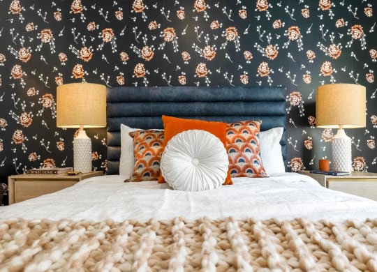 Model bedroom with blue walls and a bed with orange and white pillows