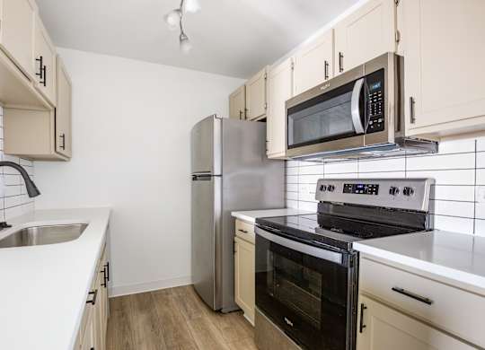 Model kitchen with a stove, oven, refrigerator, and microwave.