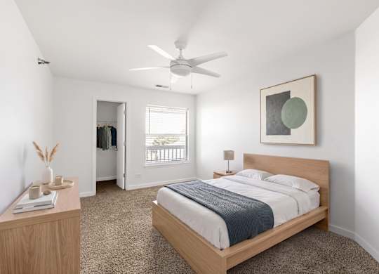 Model bedroom with a bed, nightstand, and a painting on the wall.