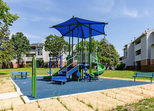 Community playground with a blue umbrella and slide.