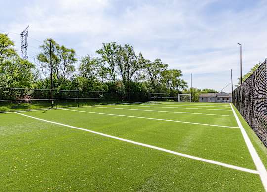 Community soccer field surrounded by a fence and trees.