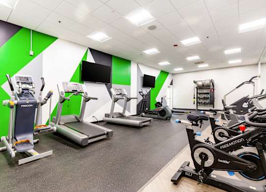 Community gym with a variety of exercise equipment including treadmills, stationary bikes, and weight machines.