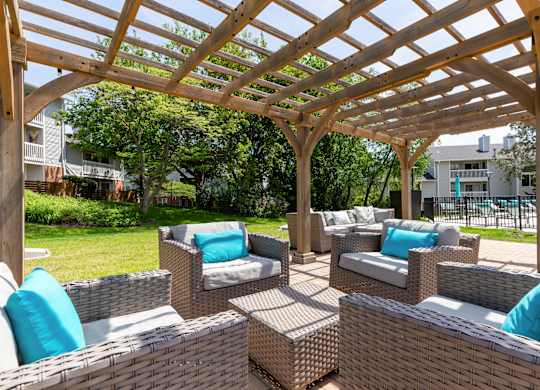 Community wooden pergola over a patio with wicker furniture.