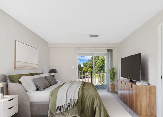 Model Bedroom with Carpet and Patio at The Commons at Haynes Farm Apartments in Boston, MA.