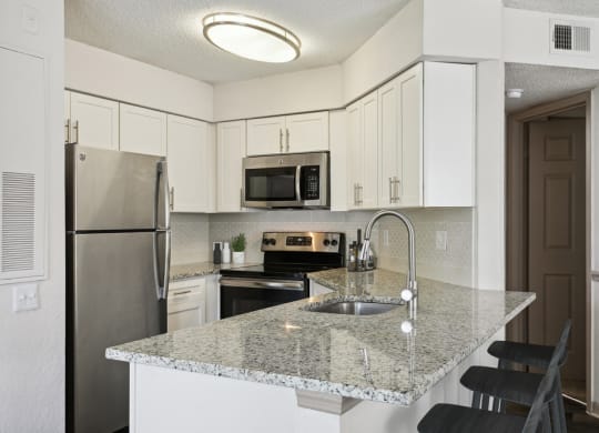 Model kitchen with white cabinets and a granite counter top at Retreat at Crosstown Apartments