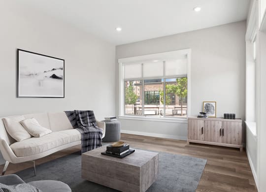 Model Living Room with Wood-Style Flooring and Window View at Seven Skies Apartments located in Sandy, UT.