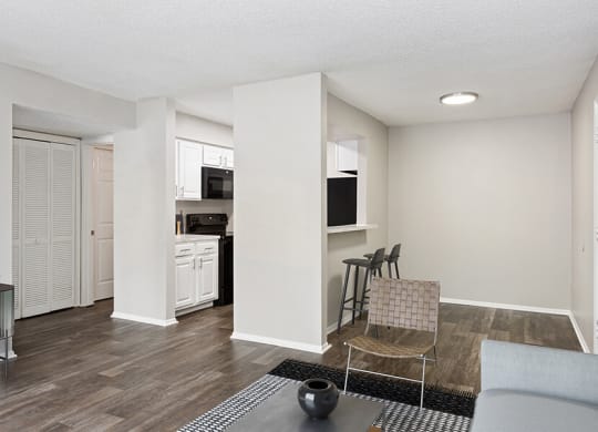 Model Living Room with Wood-Style Flooring and View of Kitchen at Grand Pavilion Apartments in Tampa, FL.
