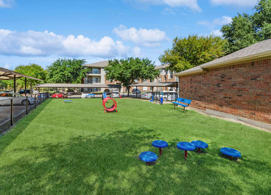 Community Dog Park with Agility Equipment at Belmont at Duck Creek Apartments in Garland, TX.
