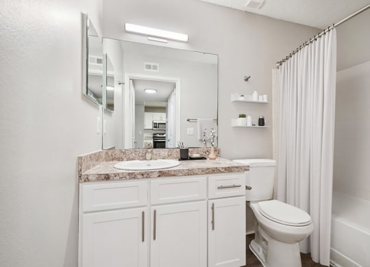 Model Bathroom with White Cabinets, Wood-Style Flooring and Shower/Tub at Westland Park Apartments in Jacksonville, FL.