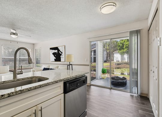 Model kitchen and living room with a sliding glass door leading to a patio at Retreat at Crosstown Apartments
