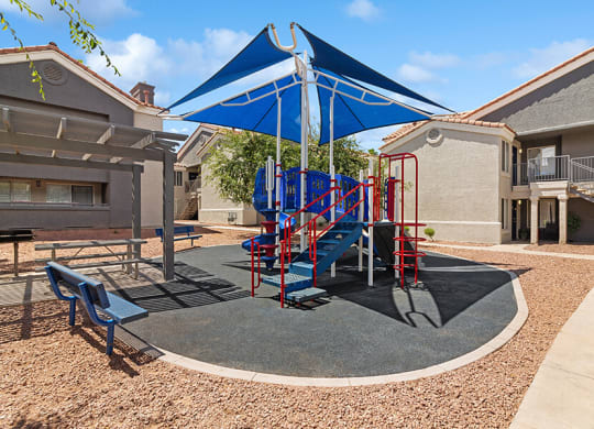 Community Playground with a Slide and Blue Canopy at Verraso Apartments in Las Vegas, NV.