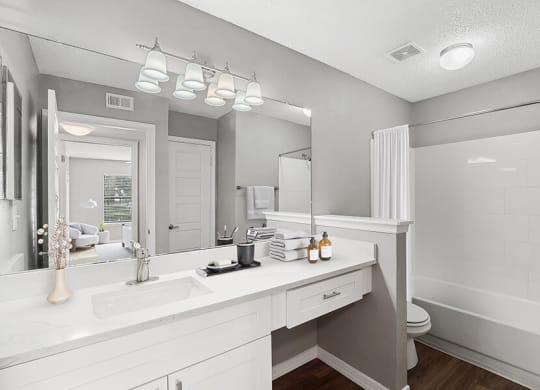 Model Bathroom with White Cabinets, Wood-Style Flooring & Shower/Tub at Fountains Lee Vista Apartments in Orlando, FL.
