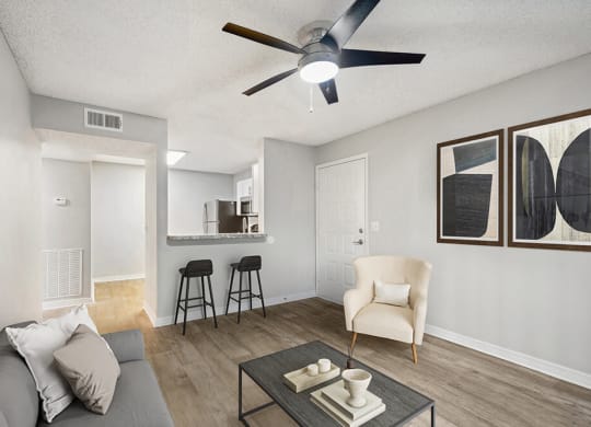 Model Living Room with Wood-Style Flooring and View of Kitchen at Westland Park Apartments in Jacksonville, FL.