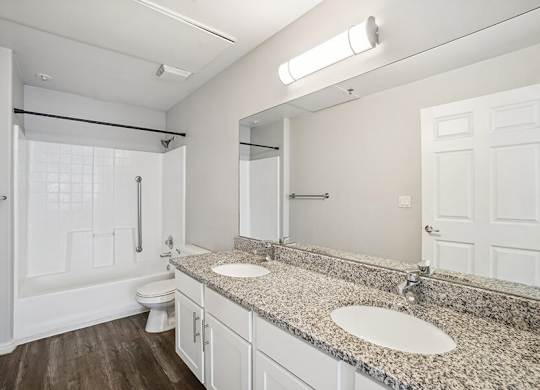 Model Bathroom with Wood-Style Flooring, White Cabinets, and Shower/Bathtub at Altitude on Fifth Apartments located in Salt Lake City, UT.