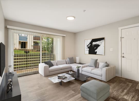 Model living room with a white couch and a coffee table in front of a large window with