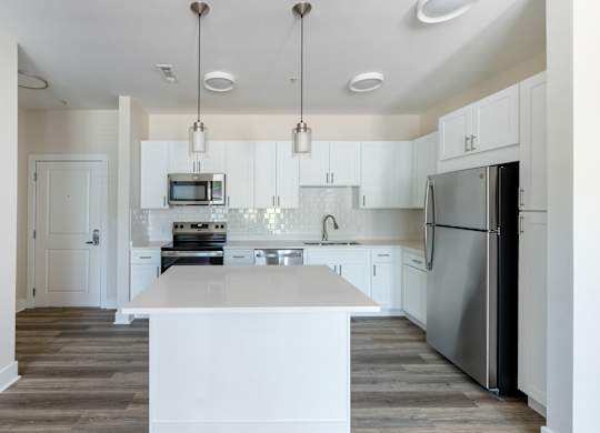A modern kitchen with a white island and stainless steel appliances.