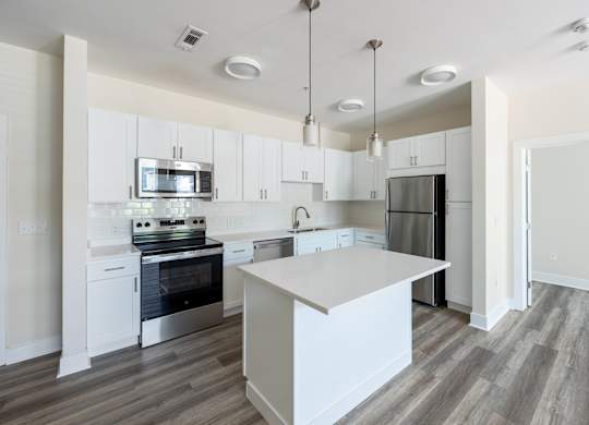 A modern kitchen with a white island and stainless steel appliances.
