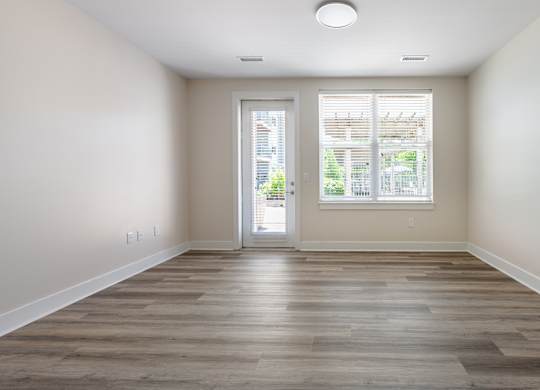A room with a wooden floor and a sliding glass door leading outside.