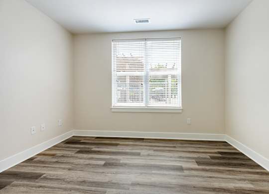 A room with a window and wooden flooring.