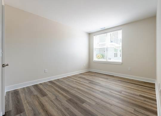 A room with wooden flooring and a window.