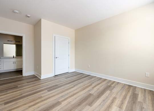 A room with a white door and wooden flooring.