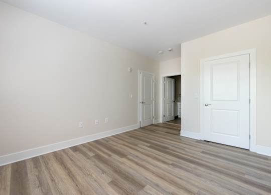 A room with a white door and a wooden floor.
