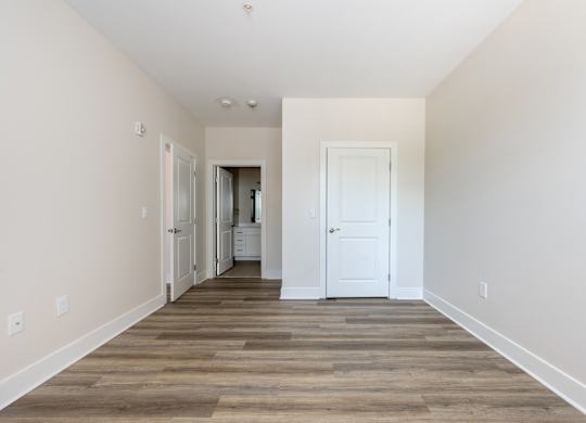 A long, empty hallway with a white door at the end.