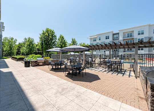 A patio with tables and chairs is surrounded by apartment buildings.