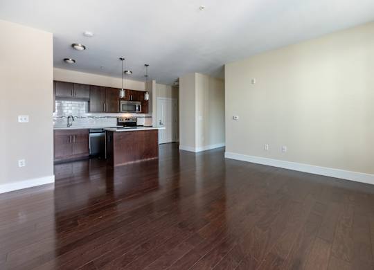A kitchen with dark wood floors and white walls.