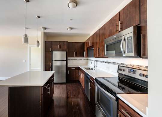 A kitchen with dark wood cabinets and stainless steel appliances.