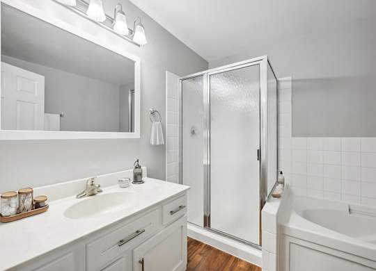 Model Bathroom with White Cabinets and Wood-Style Flooring at Dulles Green Apartments located in Herndon, VA.