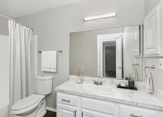 Model Bathroom with White Cabinets, Wood-Style Flooring and Shower/Tub at Grand Pavilion Apartments in Tampa, FL.