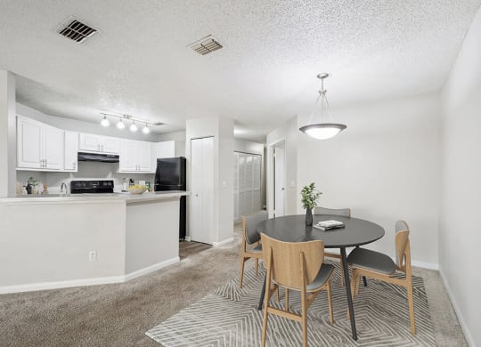 Model Dining Room with Carpet and View of Kitchen at Westland Park Apartments in Jacksonville, FL.