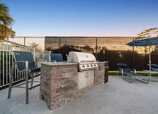 Outdoor BBQ Area with Lounge Furniture at Arbors at Orange Park Apartments located in Orange Park, FL.