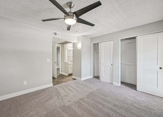 Model bedroom with a ceiling fan and carpeted floor.
