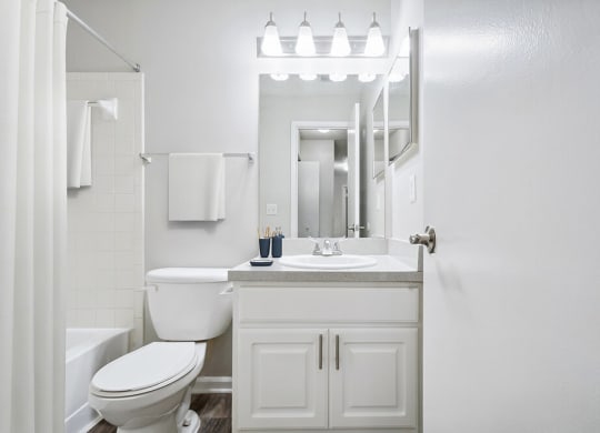 Model Bathroom with White Cabinets, Wood-Style Flooring and Shower/Tub at Westland Park Apartments in Jacksonville, FL.