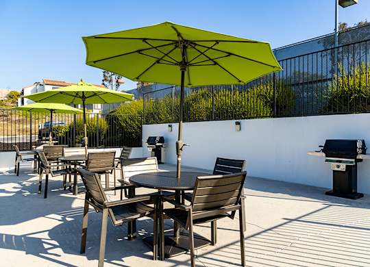 A patio with a table and chairs and a grill.