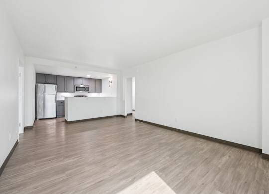 A spacious room with wooden flooring and white walls.