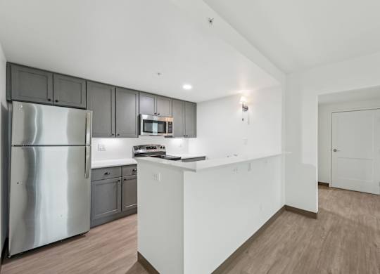 A kitchen with a refrigerator, microwave, and oven.