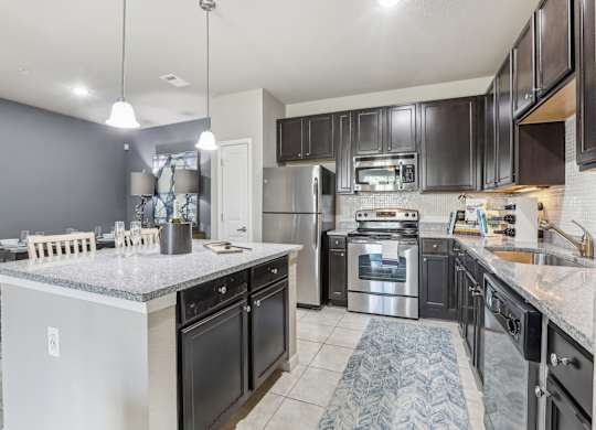 Model kitchen with a large island and stainless steel appliances.