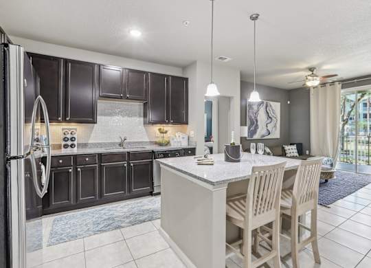 Model kitchen with a large island and wooden chairs.